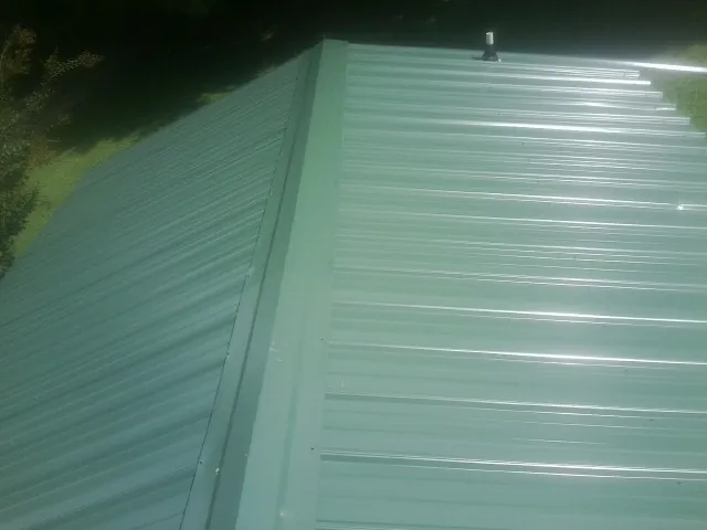 New green metal panels meeting at the ridge of a roof — Flat Roof Repair work by our crew in Pipestone