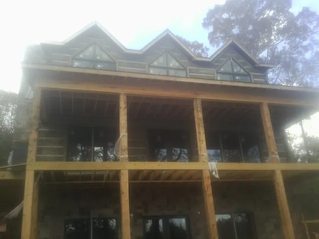 Dormers and porch framing on a large log home under construction — Roof Coating work by our crew in Pipestone