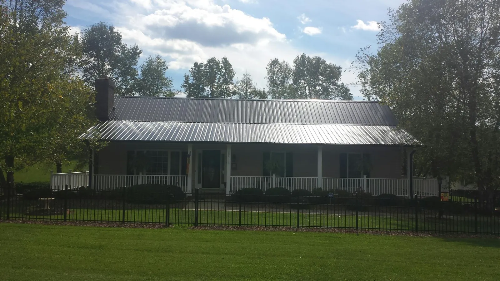 Gray metal roof on a brick ranch with a full width front porch — Gutter Guard Installation work by our crew in Pipestone