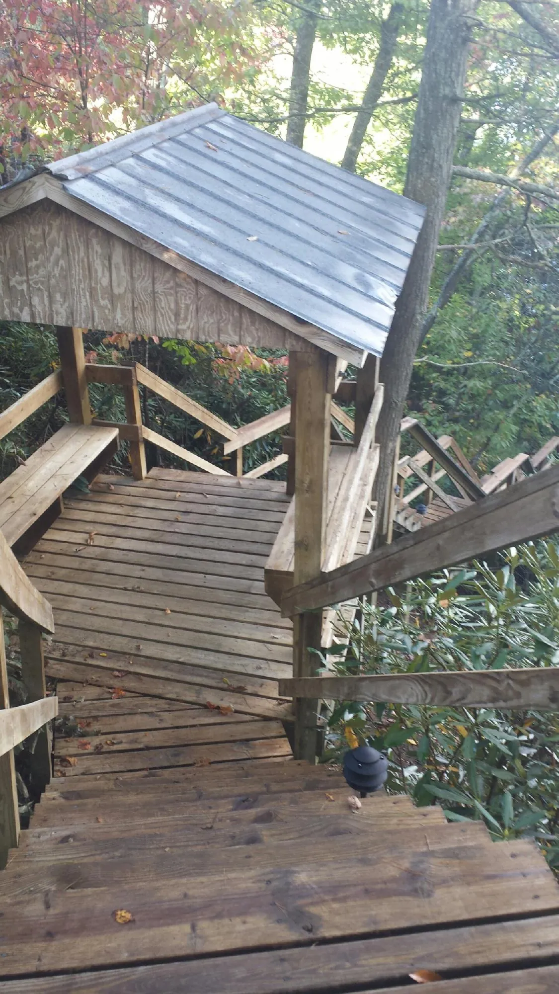 Metal roofed shelter over wooden steps on a wooded walkway — Skylight Repair & Installation work by our crew in Pipestone