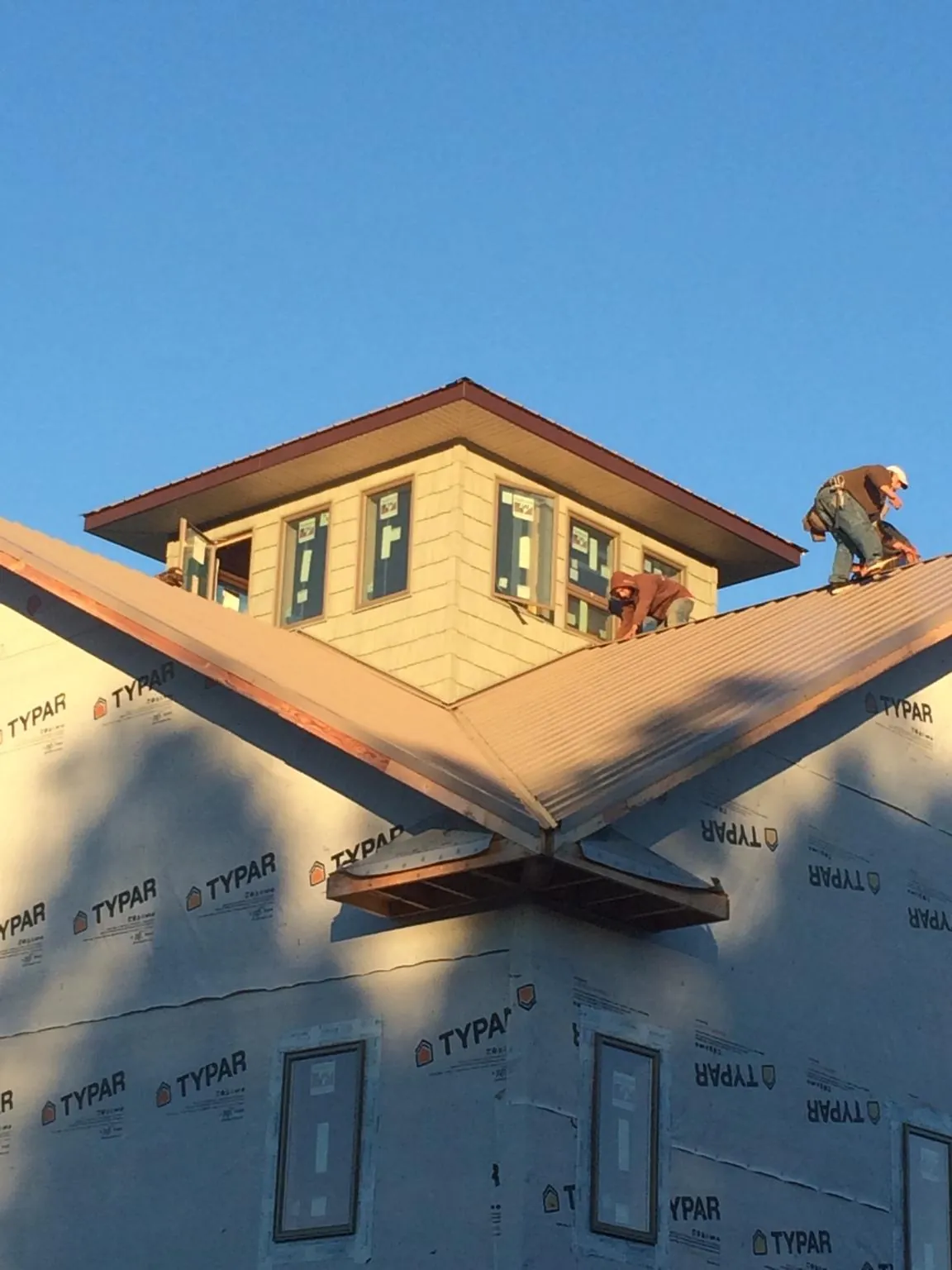 Roofers working around a rooftop cupola on a new metal roof at sunset — Roof Waterproofing in Pipestone by Roofing Brothers